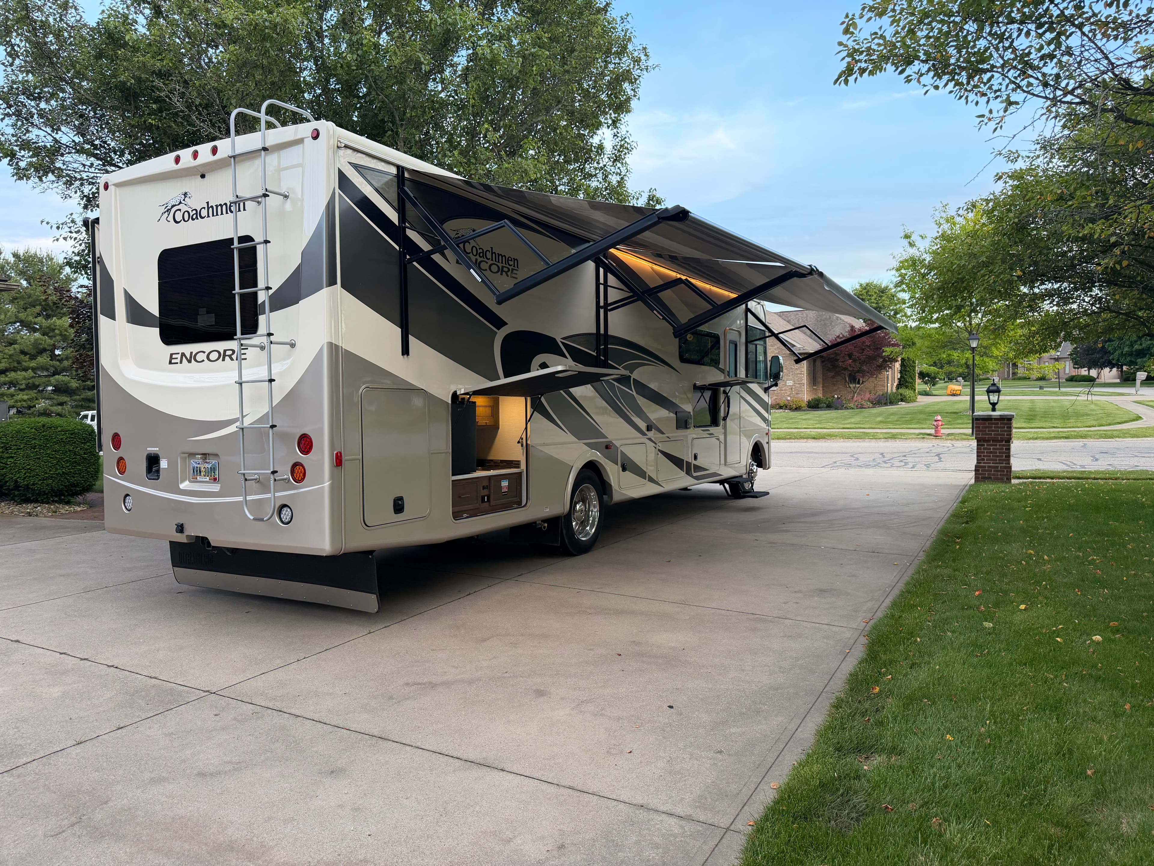 Rear passenger-side view of the Coachmen Encore RV with awning and outdoor features visible